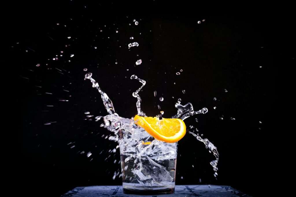 splash of water in drinking glass with sliced lemon